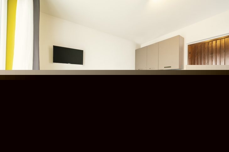 Esszimmer mit Tisch, Stühlen, Fernseher und Küchenzeile in modernem Design.