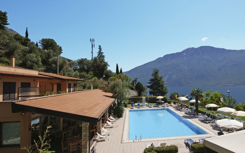 Außenansicht der Residence La Rotonda, Pool, Sonnenschirme, Berge und See im Hintergrund.