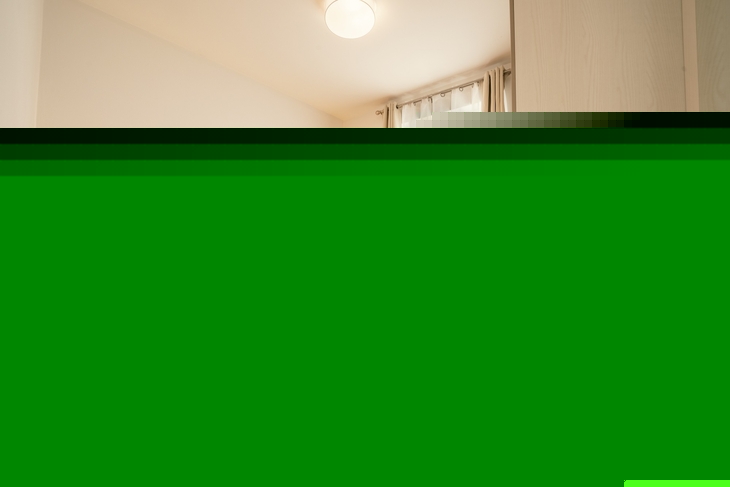 Helles Schlafzimmer mit orangefarbenem Bett, Vorhängen und Nachttisch.