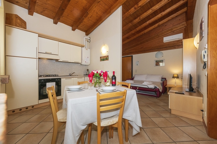 Essbereich und Küche eines Apartments mit Holzdecke und Blumen auf dem Tisch.