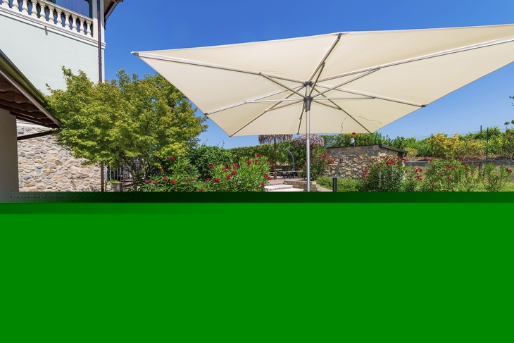 Garten mit Tisch, Stühlen und Sonnenschirm neben einem Gebäude.