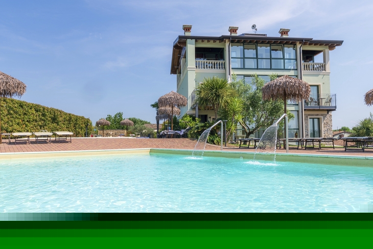 Außenansicht eines Apartments mit Pool und Sonnenschirmen im Vordergrund.