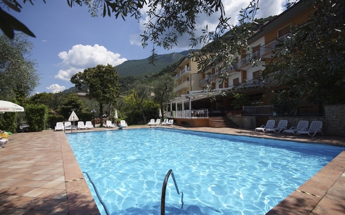 Außenpool des Residence Al Parco mit Liegestühlen und Bergen im Hintergrund.