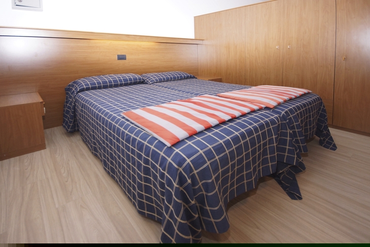 Doppelbett in einem Hotelzimmer mit kariertem Bettüberwurf.