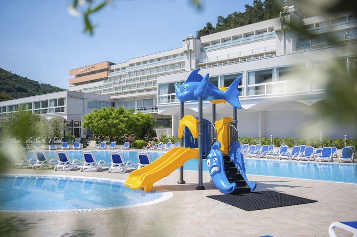 Spielplatz mit Rutsche am Pool des Hotels Narcis in Rabac, Kroatien.