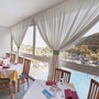 Blick aus Hotelrestaurant auf Pool und Hügel, gedeckte Tische am Fenster.