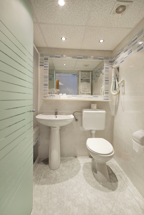 Badezimmer mit Waschbecken, Toilette und Spiegel im Hotel Narcis.