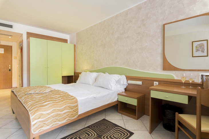Hotelzimmer mit Doppelbett, Schreibtisch, Kleiderschrank und Balkon.