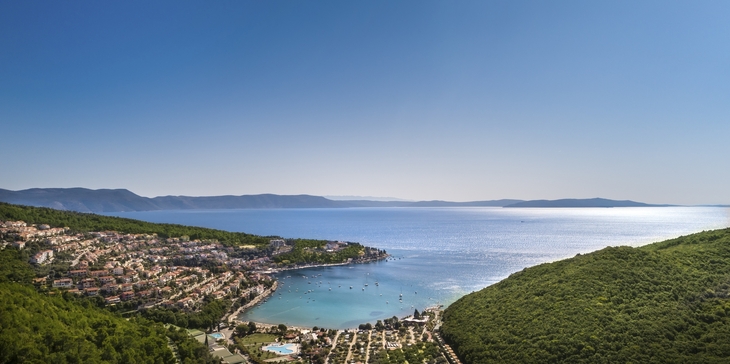 Panoramablick auf Rabac mit Küste und grünem Hügel im Vordergrund