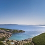 Panoramablick auf Rabac mit Küste und grünem Hügel im Vordergrund