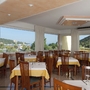 Speisesaal im Hotel Hedera mit Blick auf grüne Hügel und Fenster im Hintergrund.