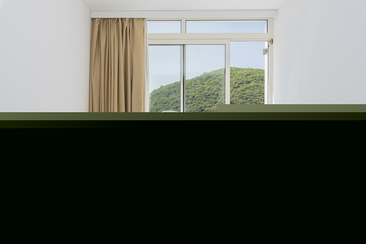 Hotelzimmer mit Doppelbett und Balkon mit Meerblick.