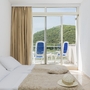 Hotelzimmer mit Doppelbett und Balkon mit Meerblick.