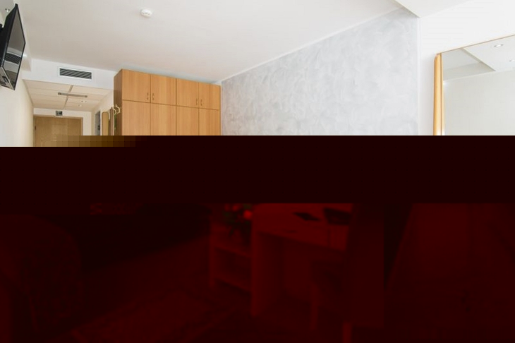 Helles Hotelzimmer mit Doppelbett, Schreibtisch und Schrank in modernem Design.