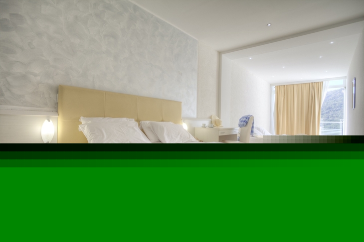 Helles Hotelzimmer mit zwei Betten und Meerblick durch ein großes Fenster.