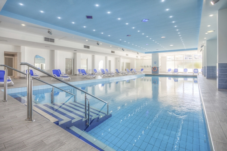 Innenpool im Hotel Hedera mit Liegestühlen am Rand.