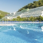 Außenansicht des Hotel Hedera mit Pool und umliegenden Hügeln.