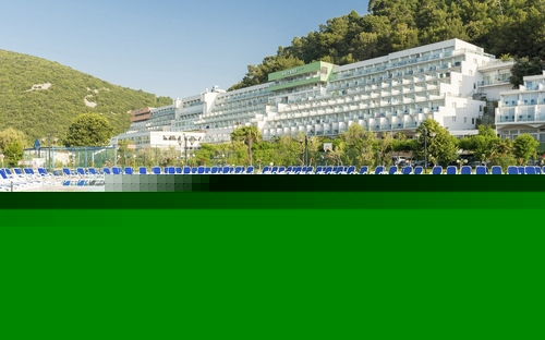 Außenansicht des Hotel Hedera mit Pool und umliegenden Hügeln.
