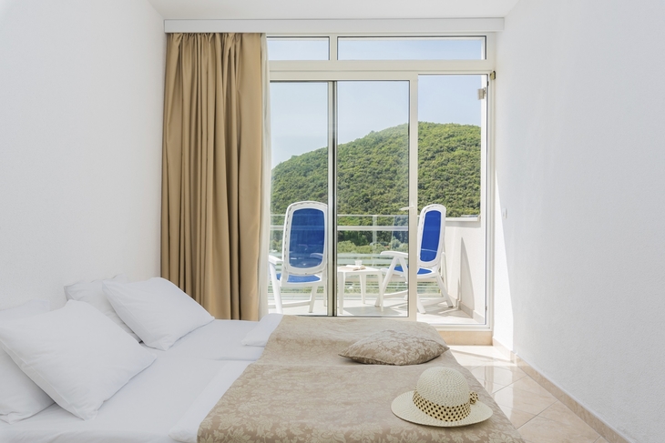 Hotelzimmer mit Doppelbett und Balkon mit Meerblick.