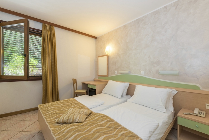 Standardzimmer im Hotel mit Doppelbett, Schreibtisch und offener Fensteransicht.