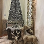 Weihnachtlich geschmücktes Zimmer mit glitzerndem Baum und Rentierfiguren.