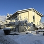 Verschneite Obstwiese mit Wohnhaus am Bodensee bei klarem Winterhimmel.