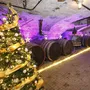 Weihnachtsbaum in einem festlich beleuchteten Weinkeller mit Fässern.