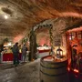 Weihnachtsmarkt in einem Weinkeller mit dekorierten Ständen und Besuchern.