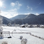 Winterlandschaft in Oberwössen mit schneebedeckten Häusern und Bergen bei Sonnenschein