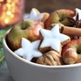 Schale mit Weihnachtsgebäck, Äpfeln, Nüssen und Zimtstangen.