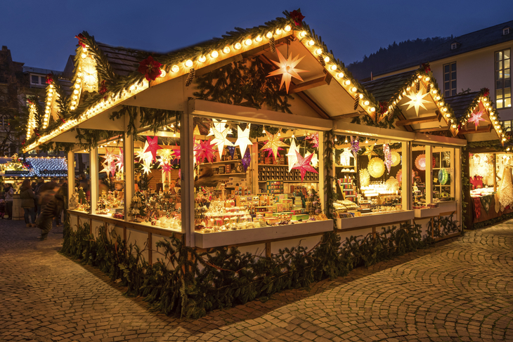 Beleuchteter Weihnachtsmarktstand mit Dekorationen und Waren bei Nacht.