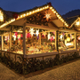 Beleuchteter Weihnachtsmarktstand mit Dekorationen und Waren bei Nacht.