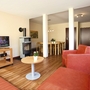 Wohnzimmer mit rotem Sofa, kleinem Tisch, Ofen, Fernseher und Esstisch mit Stühlen in der Ferienanlage Prüm.