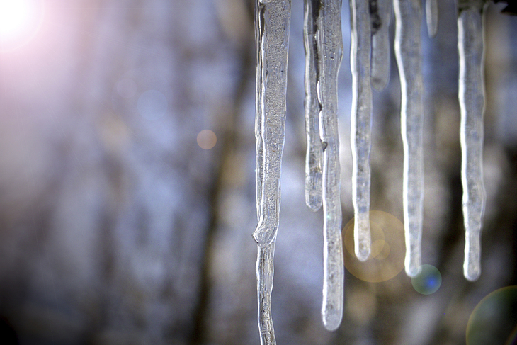 Eiszapfen im Sonnenlicht hängen von einer Kante herunter.