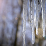 Eiszapfen im Sonnenlicht hängen von einer Kante herunter.