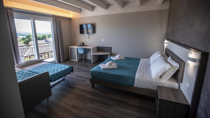 Hotelzimmer mit Doppelbett, Einzelbett, Schreibtisch und Balkonblick