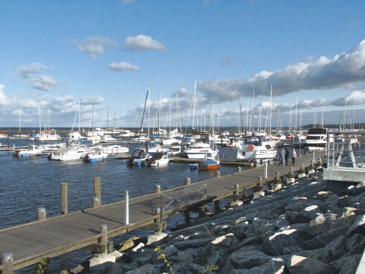 Boote am Pier im Hafen von Kühlungsborn bei blauem Himmel und Wolken.