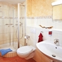 Helles Badezimmer mit Dusche, WC und Waschbecken in einer Ferienanlage.