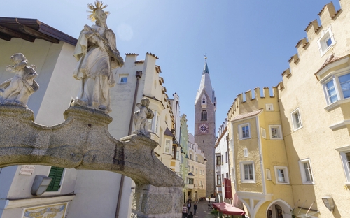 Historische Altstadt von Brixen mit Skulpturen und Kirchturm.
