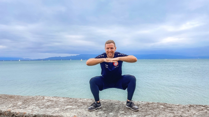 Eine Person macht Yoga an einem See bei bewölktem Himmel.