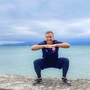 Eine Person macht Yoga an einem See bei bewölktem Himmel.