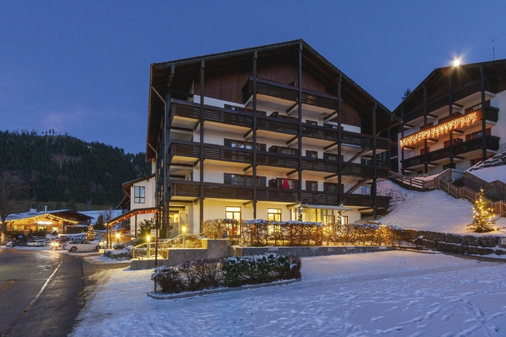 Alpenresidenz in Berchtesgaden im Schnee, beleuchtet bei Dämmerung.