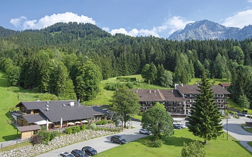 Alpenresidenz in Berchtesgaden umgeben von Bäumen und Bergen im Sommer.