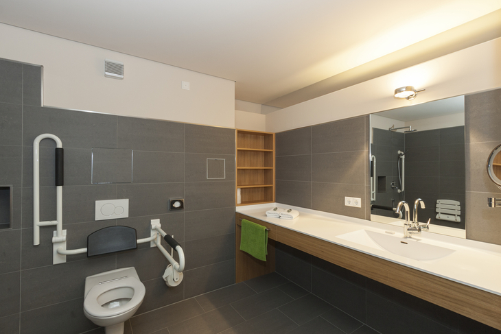 Barrierefreies Badezimmer mit Haltegriffen und breitem Waschbecken.