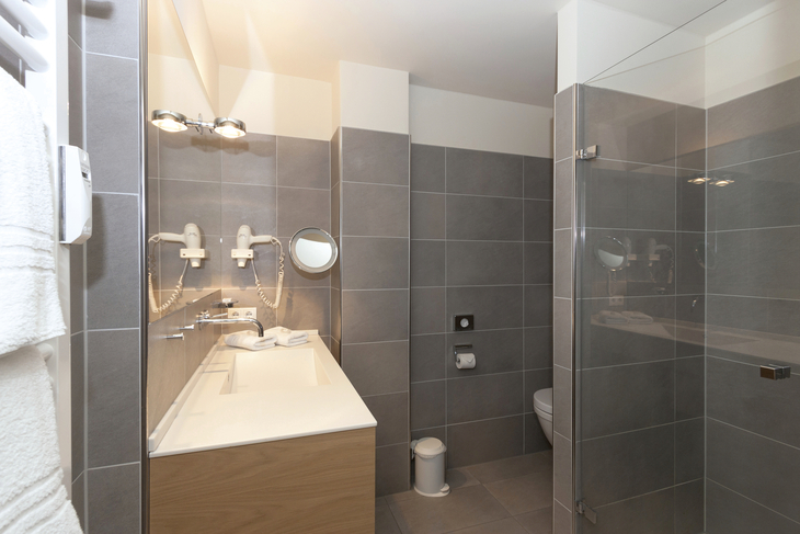 Modernes Badezimmer mit Glasdusche und Waschtisch in einem Hotelzimmer.