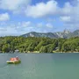 Pedalboot auf dem Klopeiner See vor bewaldeten Bergen und blauem Himmel.