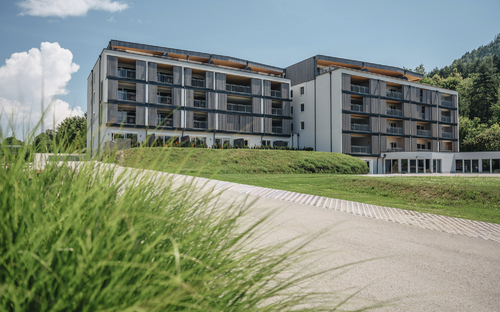Modernes Resortgebäude in St. Kanzian am Klopeiner See, umgeben von Grünflächen.
