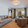 Modernes Wohnzimmer mit Sofa, Sesseln und Blick auf einen Balkon.
