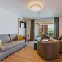Modernes Wohnzimmer mit Sofa, Sesseln und Blick auf einen Balkon.