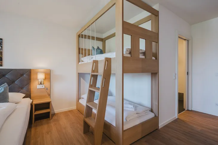 Etagenbett im hellen Zimmer eines Resorts mit Holzmöbeln.
